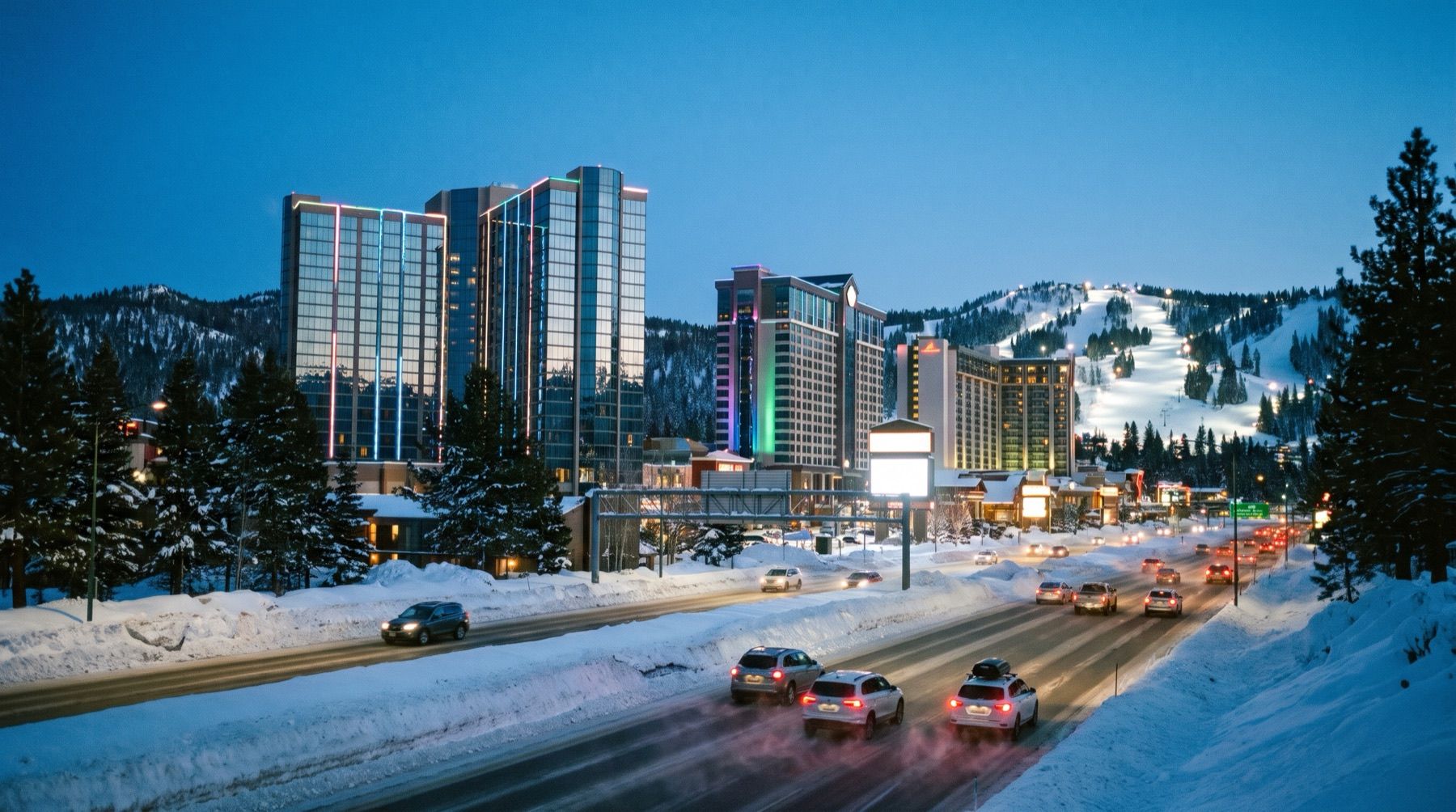 Casino-hotel towers at Stateline on a snowy evening, traffic on the highway in front and lit ski runs on the mountain behind