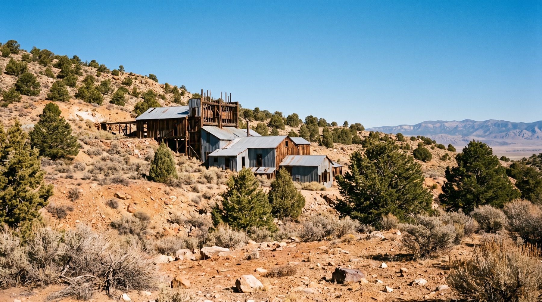 Weathered wooden mill building in the ghost town of Berlin surrounded by sagebrush and juniper trees