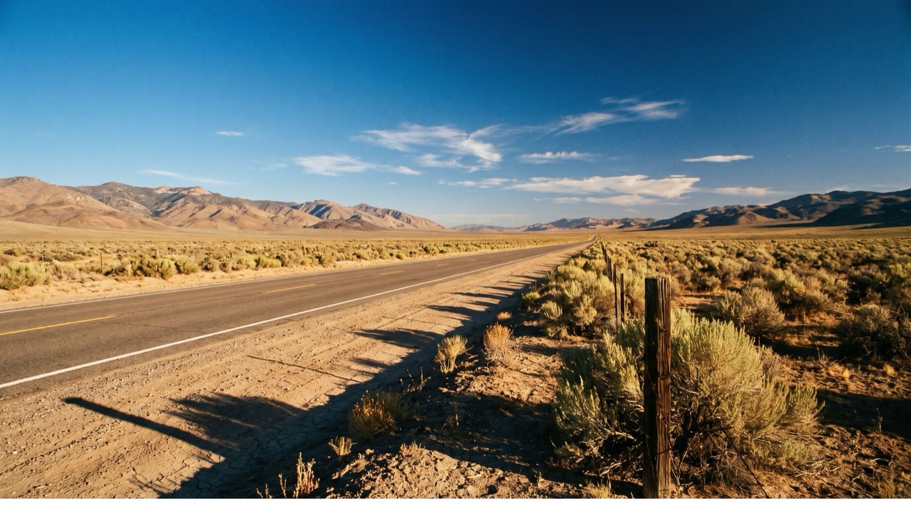 A long straight stretch of Highway 50 cutting through a sagebrush valley toward mountains in central Nevada.