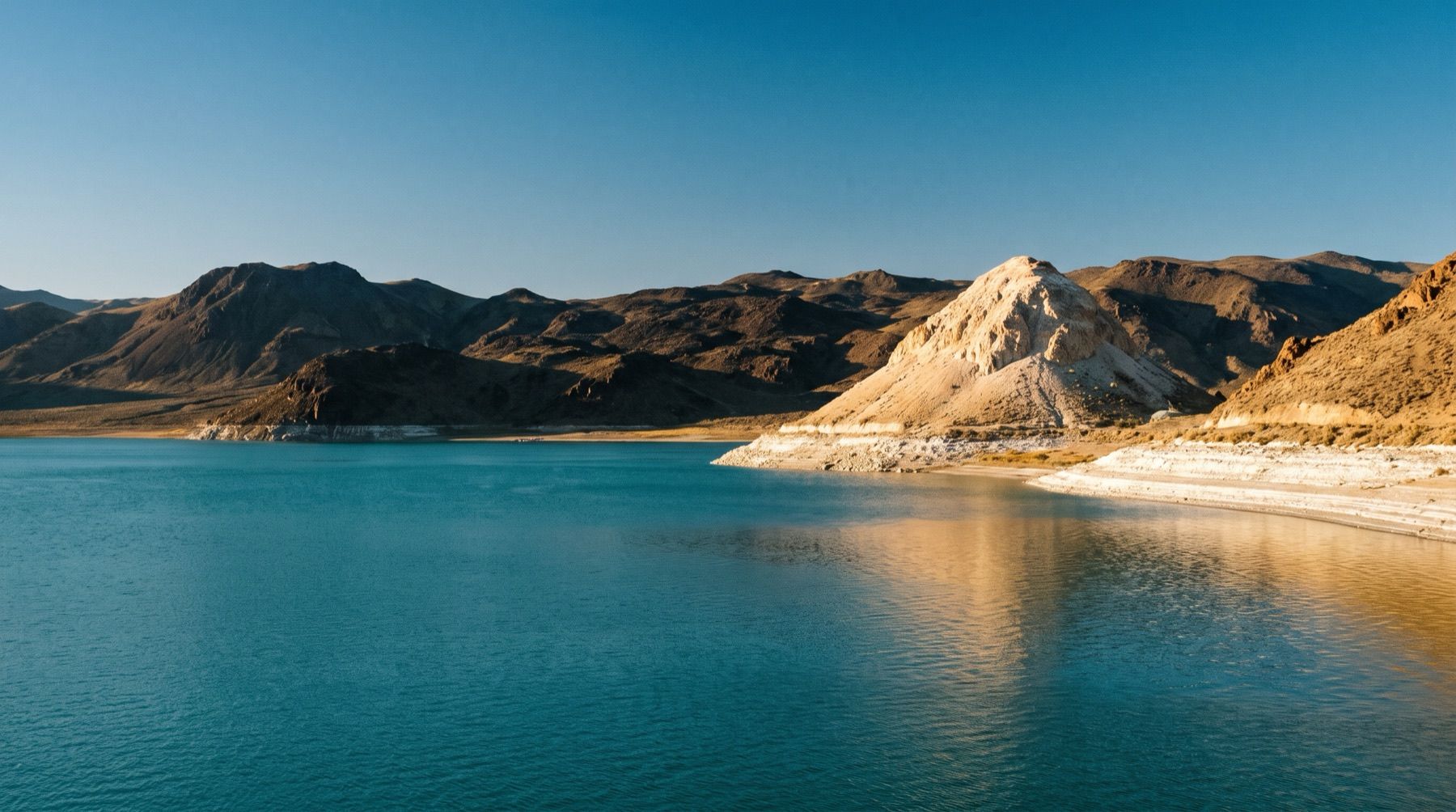 Pyramid Island rises from the blue waters of Pyramid Lake in Nevada with dry mountain ridges behind it.
